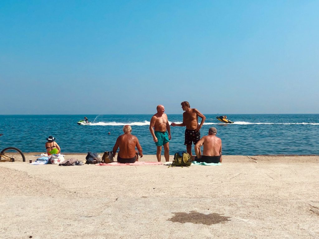 3 women and 2 men sitting on beach sand during daytime