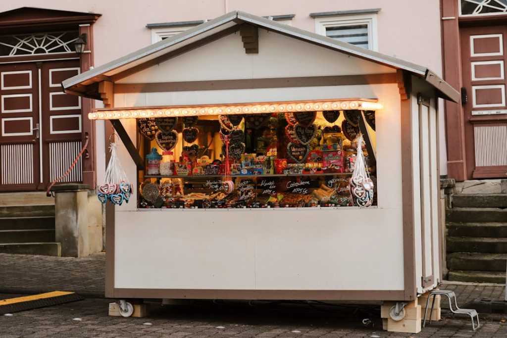 Free Festive Christmas market stall selling candies and treats at dusk. Stock Photo