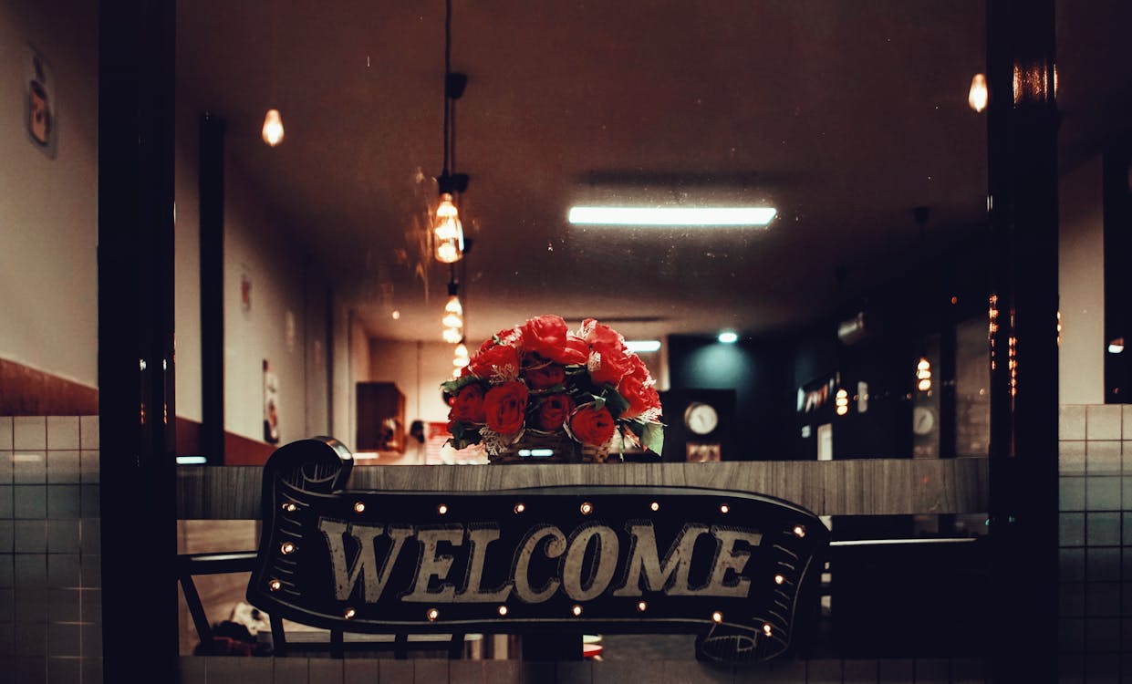 Free Warm and inviting restaurant interior with a welcoming sign and flower bouquet. Stock Photo